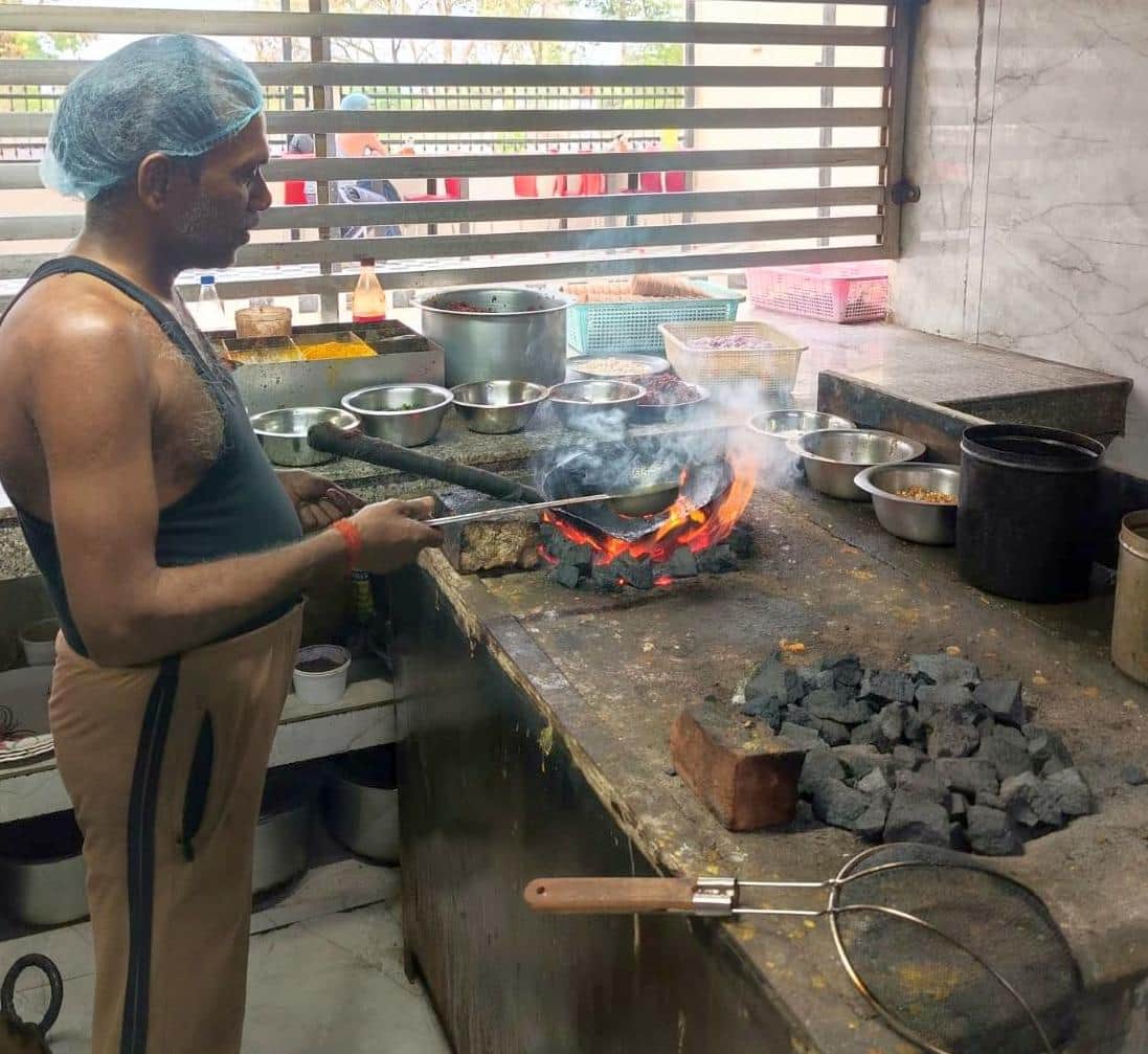 जनता ढाबा पर कोयले की भट्टी पर भोजन बनाता कारीगर।