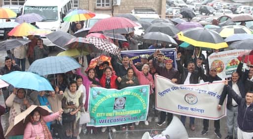 धर्मशाला में छाता लेकर बारिश के बीच मांगों के समर्थन में रैली निकालते पेंशनर। -अमर उजाला