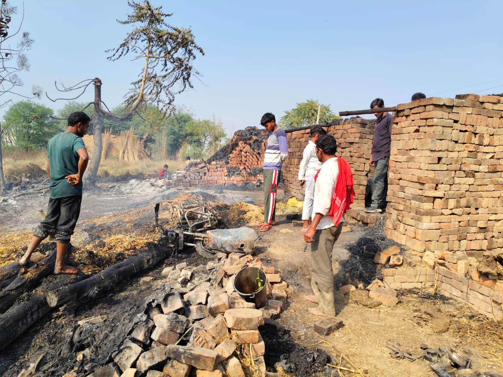 विलासपुर गांव में आग पर काबू पाने के बाद जली बाइक देखते ग्रामीण, संवाद