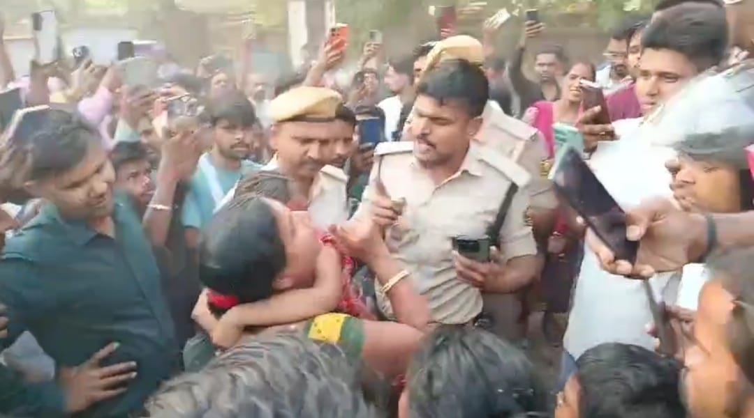 भीड़ से महिला को बचाते पुलिस