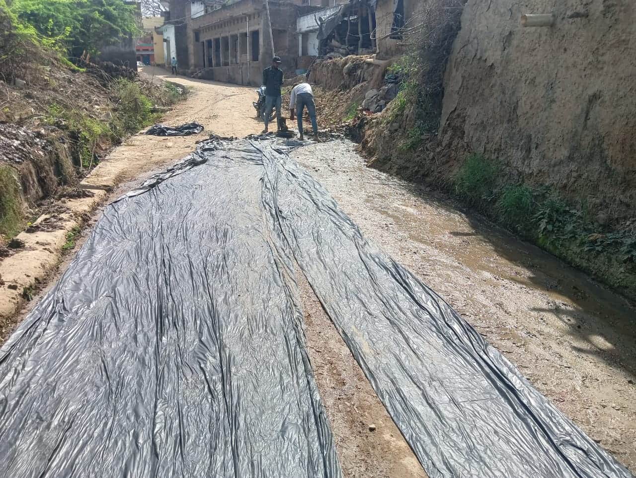 फोटो - 17 कीचड़ के ऊपर बिछी काली पन्नी और कार्य करते मजदूर। संवाद