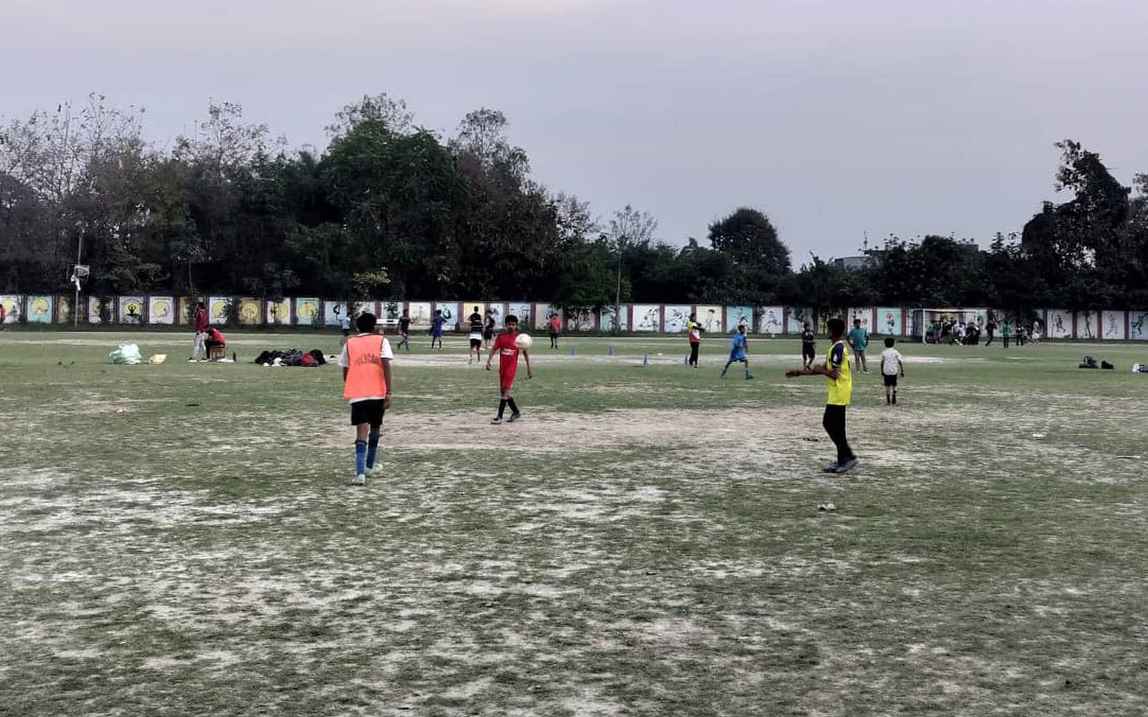 स्टेडियम में फुटबॉल का अभ्यास मैच खेलते खिलाड़ी।