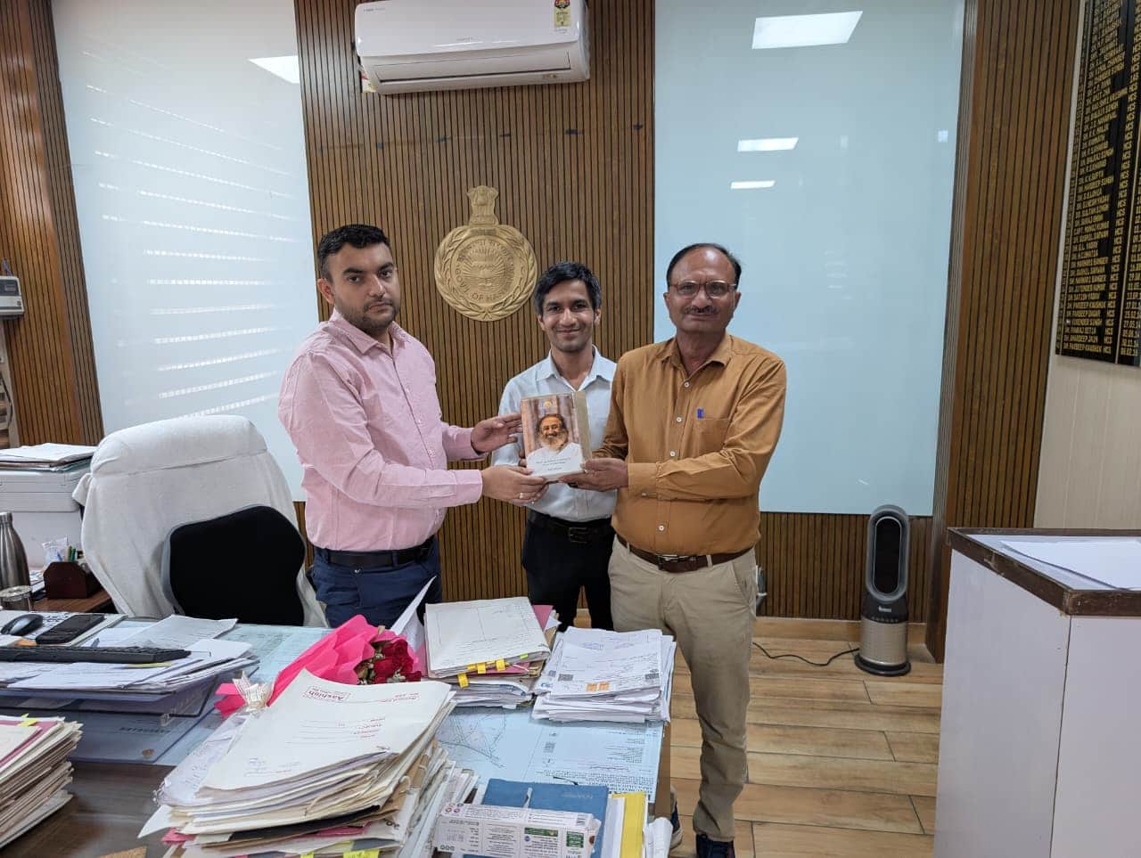 17jjrp19- एसडीएम बहादुरगढ़ को किताब भेंट करते आर्ट ऑफ लिविंग के स्टेट कोऑर्डिनेटर राजवीर सिंह 