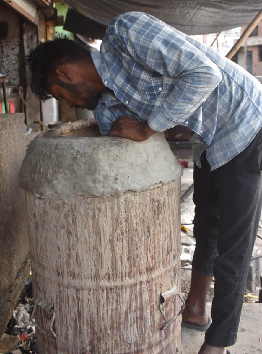 गांधी पार्क बस स्टैंड स्थित एक  होटल पर तंदूर में गोयला लगाता कर्मचारी।
