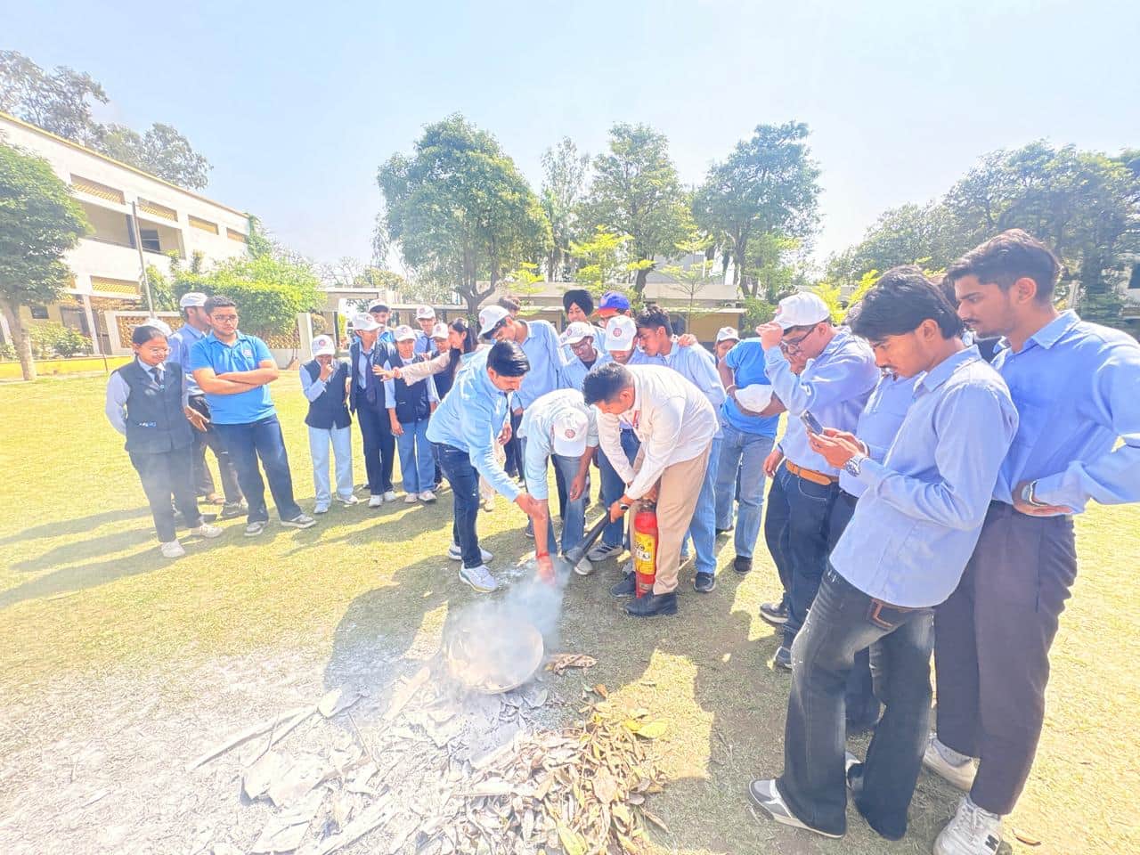 विद्यार्थियों को आग बुझाने की जानकारी देते दमकल कर्मी। संस्थान