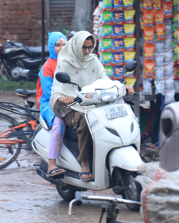 अंबाला में हो रही बरसात में भीगते हुए  गंतव्य की और जाती एक्टिवा सवार युवती। संवाद
