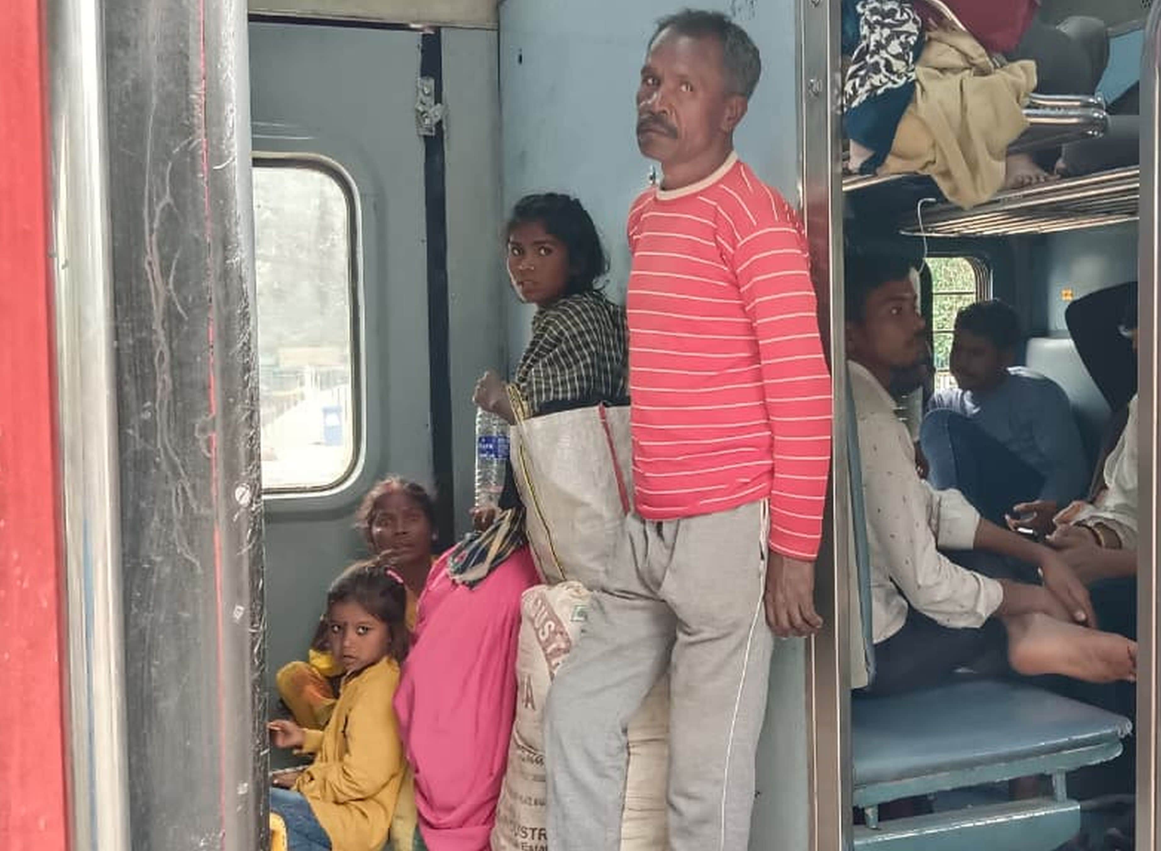 अकबरपुर रेलवे स्टेशन पर दून एक्सप्रेस में बाथरूम के पास बैठकर यात्रा करते लोग।-