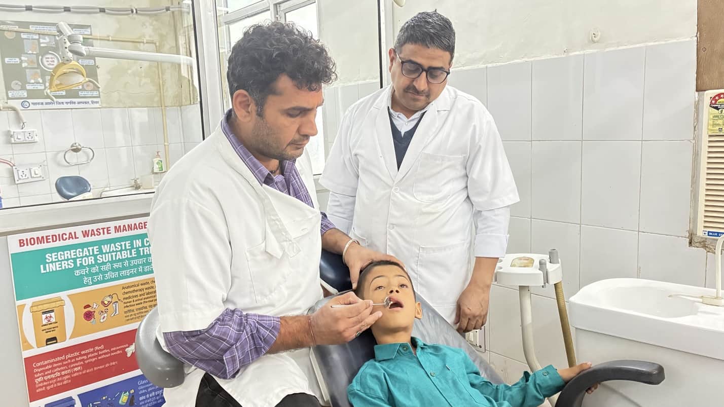 बच्चे के दांत की जांत करते डॉ विक्रम पंघाल और डॉ बंसी लाल बेनिवाल