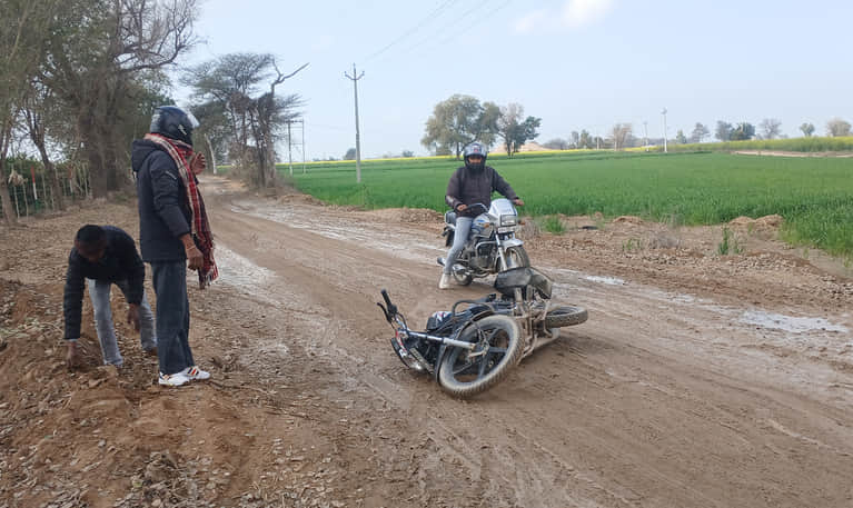 रोड पर फिसलन होने से गिरा बाइक और पास खड़े लोग। 