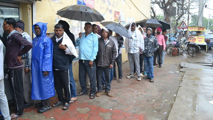 Gas crisis: Waiting for cylinder booking under umbrella in rain