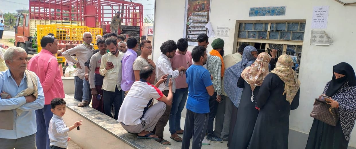 They stood in line for a gas cylinder, getting soaked in the rain.