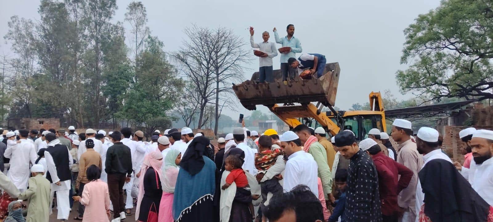बुलडोजर पर चढ़कर नमाजियों पर फूल बरसाते लोग।
