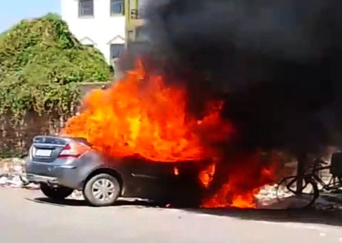 A car parked near a garbage dump outside a hotel burst into flames.