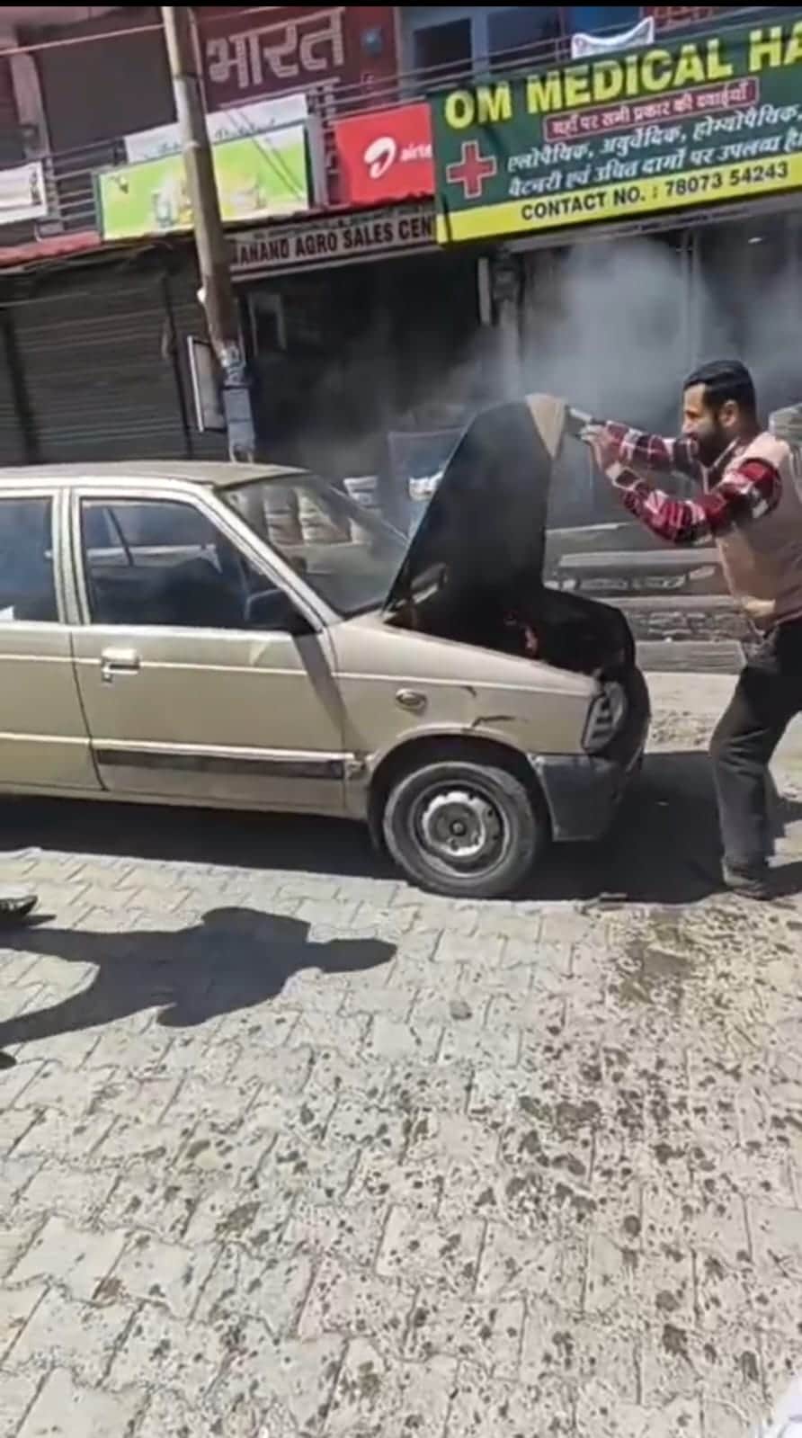 राजगढ़ में खड़ी कार में लगी आग को बुझाते लोग। संवाद