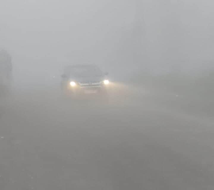 सुबह के समय घने कोहरे से गुजरती कार फोटो संवाद