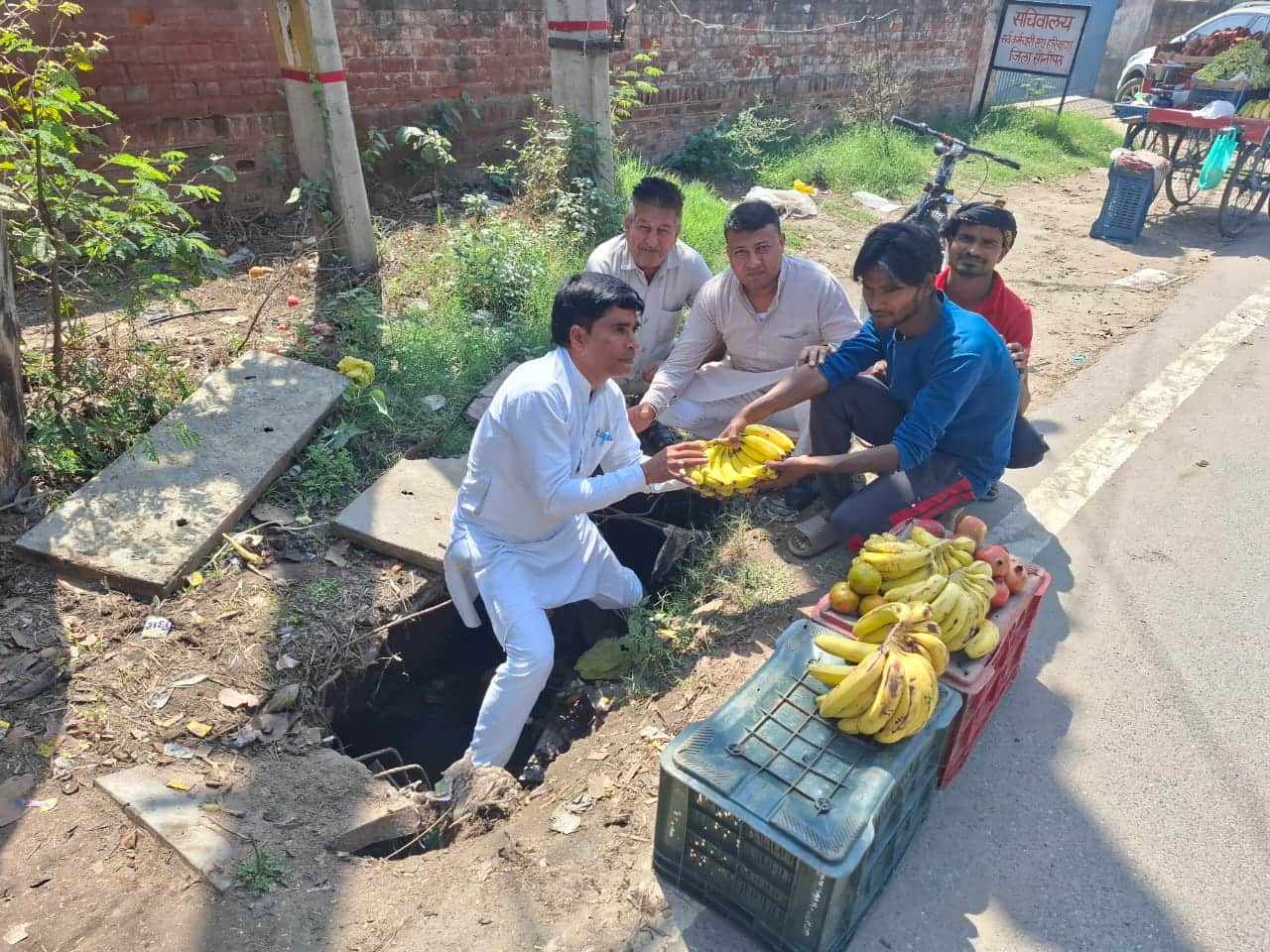 सड़क किनारे गड्ढे में बैठकर केले बेचते जिला पार्षद संजय बड़वासनिया। स्रोत : प्रवक्ता