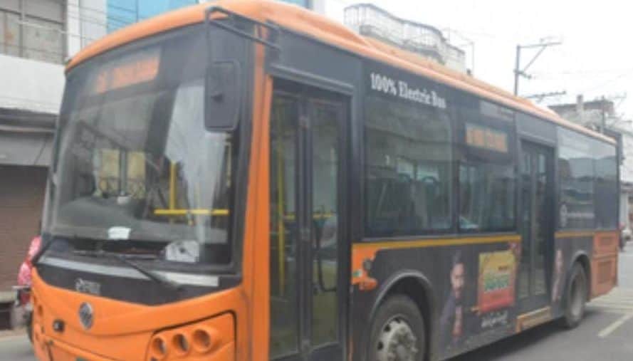 शहर की संकरी सड़क से निकलती  ई-बस। संवाद