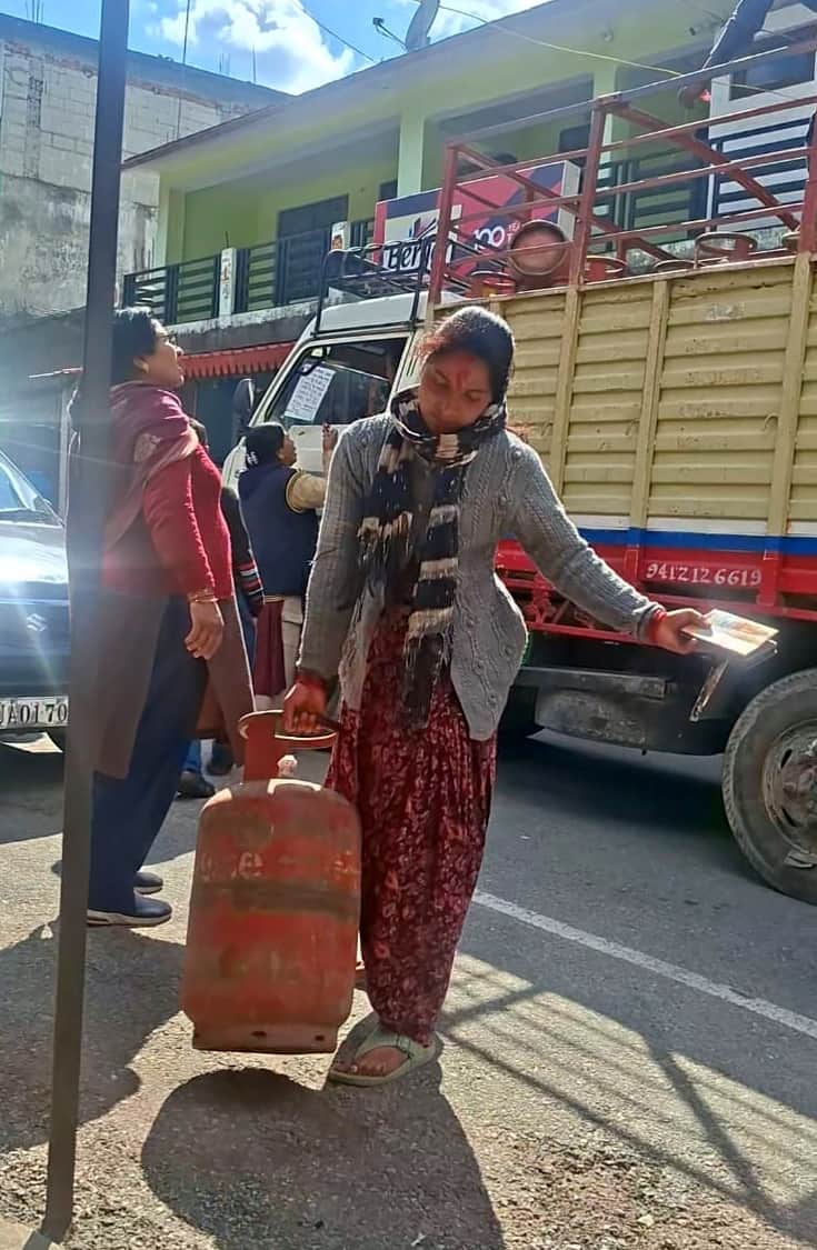 धरमघर में सिलिंडर रिफिल करवाकर  जाती महिला। संवाद