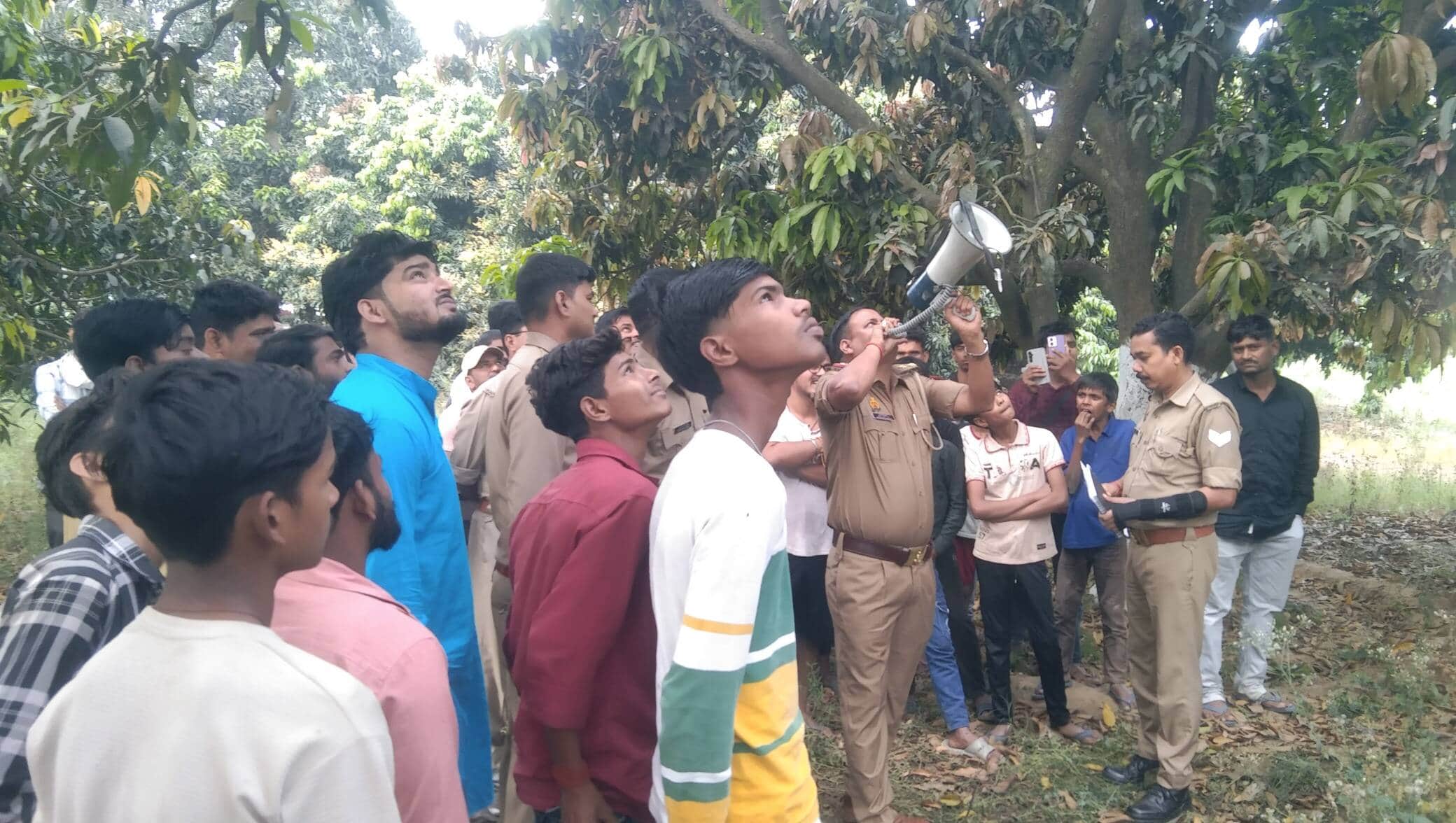 बलुआ तकिया गांव में टावर पर चढ़े बुजुर्ग से नीचे उतरने की अपील करते थानाध्यक्ष पटहेरवा धीरेन्द्र