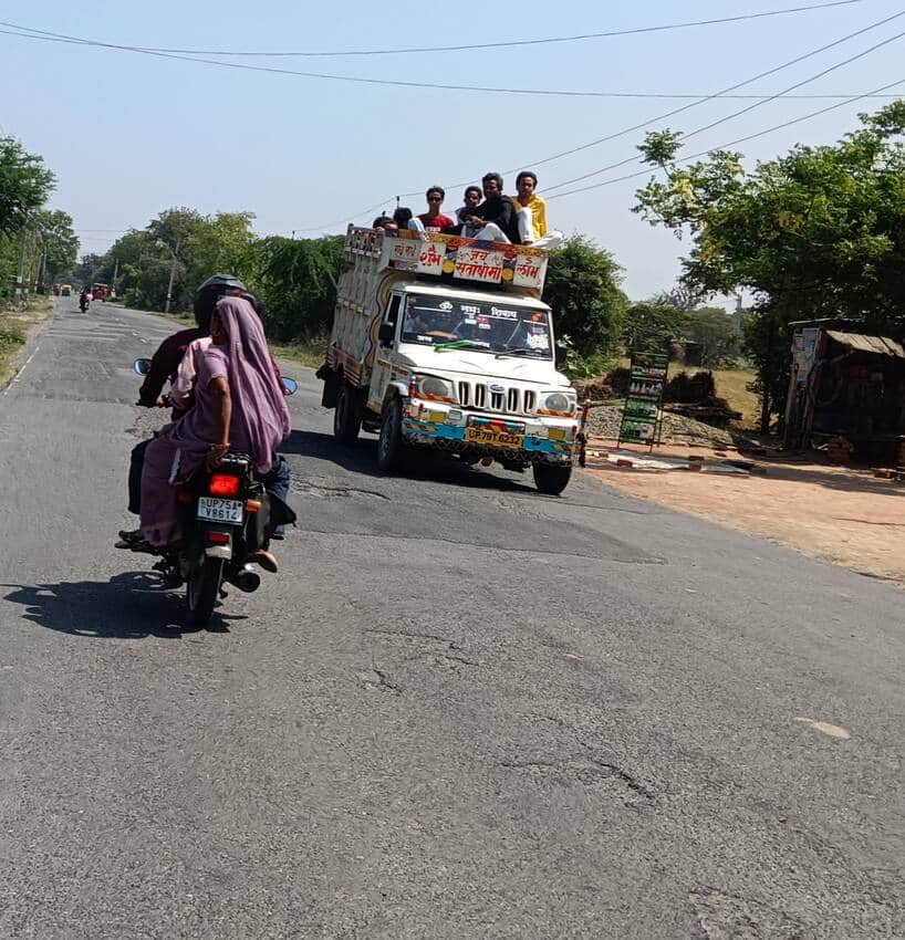 फोटो-3-पिकअप वाहन के डाले पर बैठकर यात्रा करते लोग।संवाद