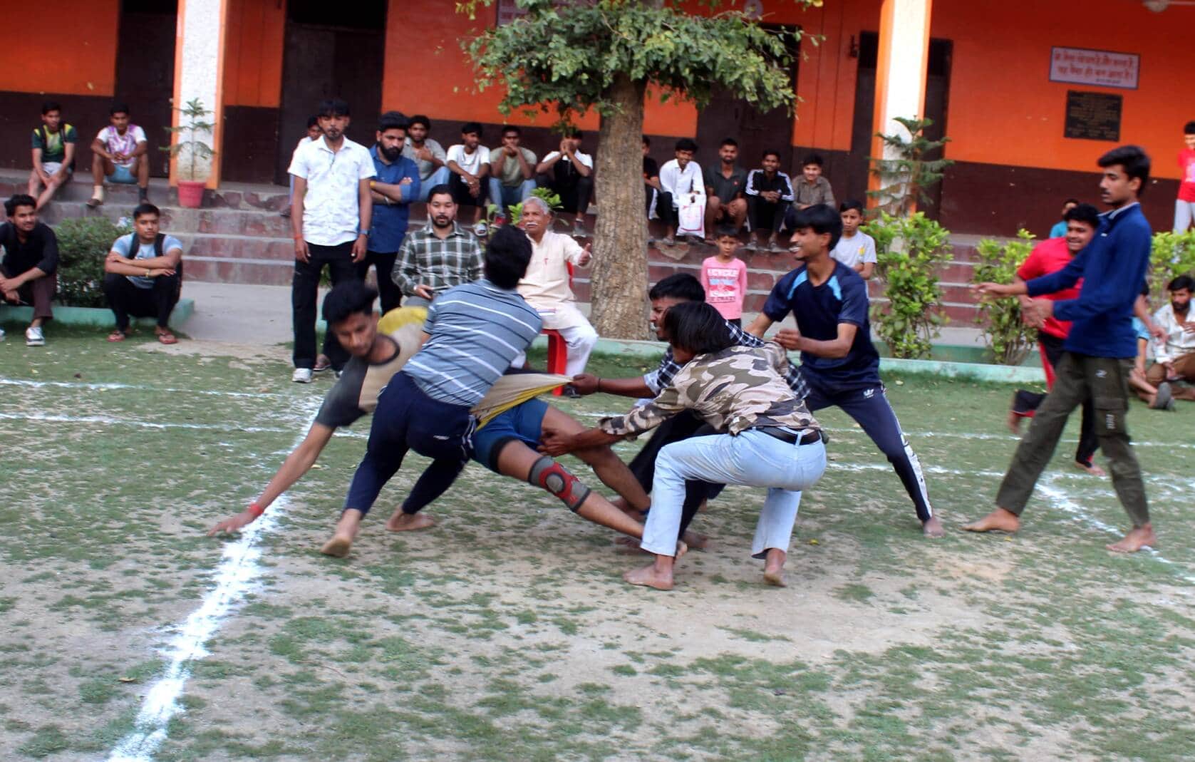 कबड्डी प्रतियोगिता के दौरान खिलाड़ी को पकड़ते प्रतिद्वंद्वी टीम के खिलाड़ी। संवाद