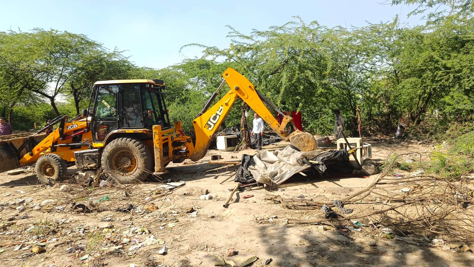सरकारी जमीन पर बनीं झुग्गियों को हटाती जेसीबी।