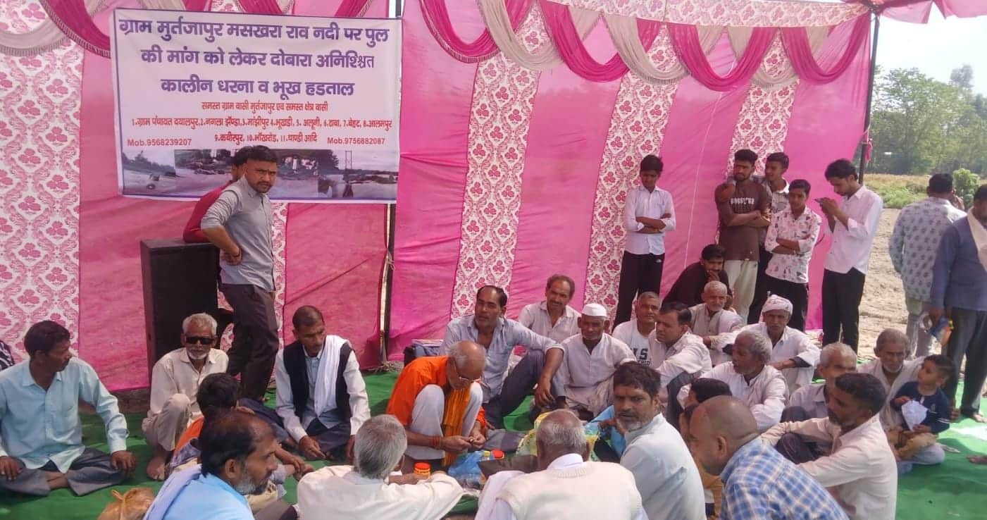 बेहट के गांव मुर्तजापुर में नदी किनारे धरना देते ग्रामीण। संवाद