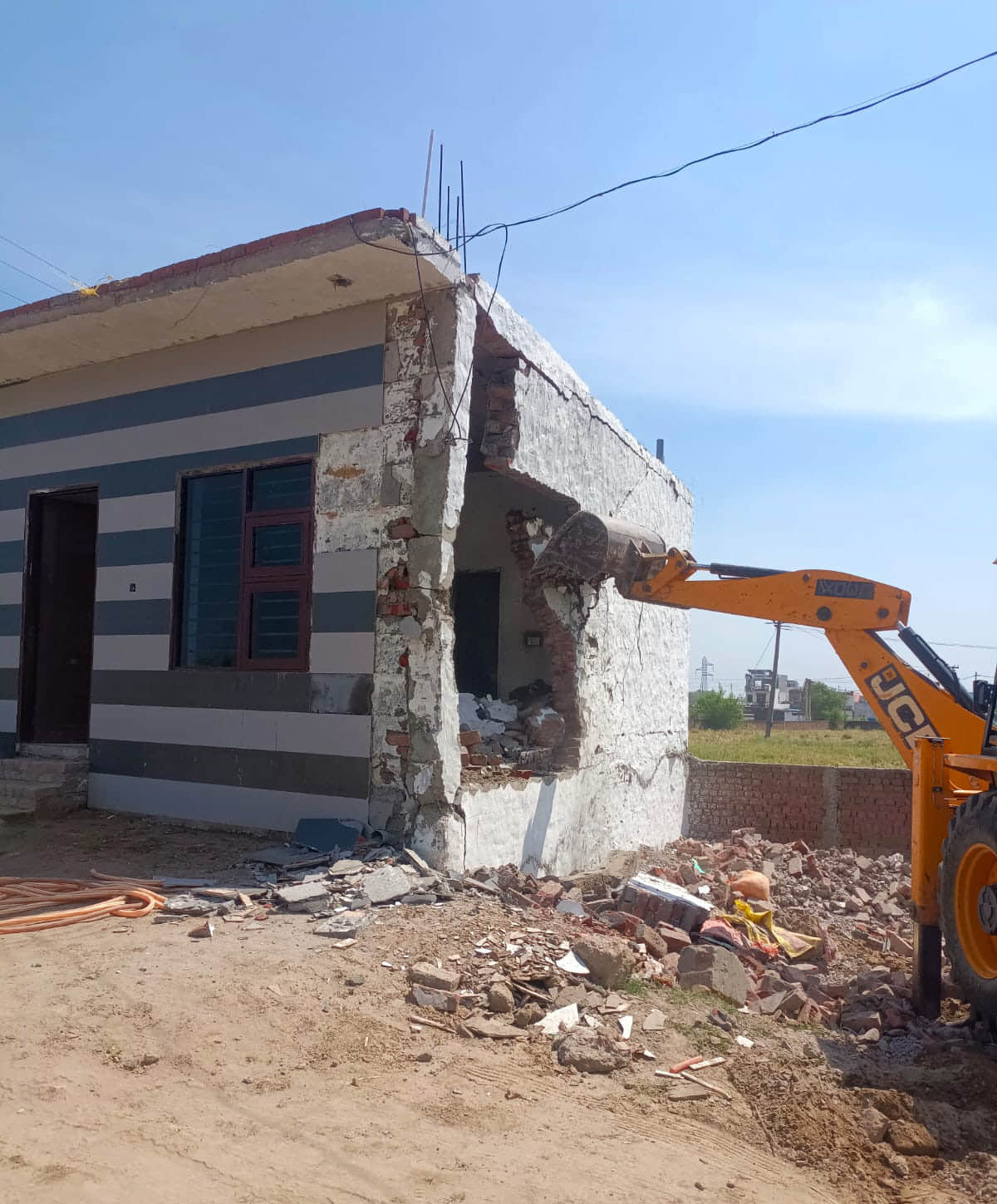 जेसीबी से अवैध निर्माण गिराता चालक। डीटीपी