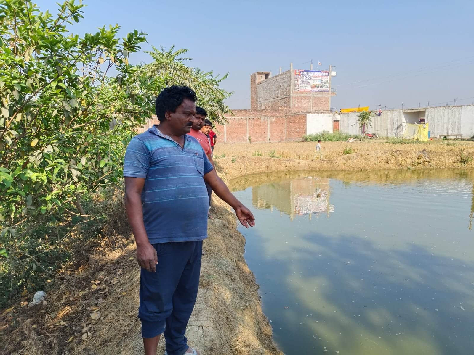 कसेंदा गांव के बाहर स्थित तालाब पर में मरी मछलियां दिखाता किसान, स्रोत स्वयं