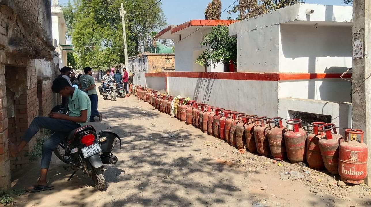 अहरौला थाने के बगल में सिलिंडर की लाइन लगाकार फूलपुर गैस एजेंसी के गाड़ी का इंतजार करते लोग। सं