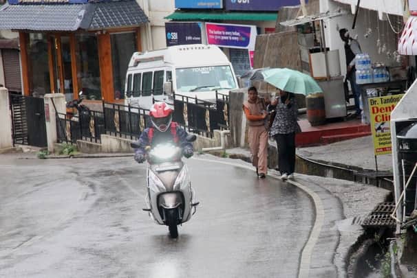 धर्मशाला में रविवार को बारिश के बीच गुजरते हुए दोपहिया चालक। अमर उजाला