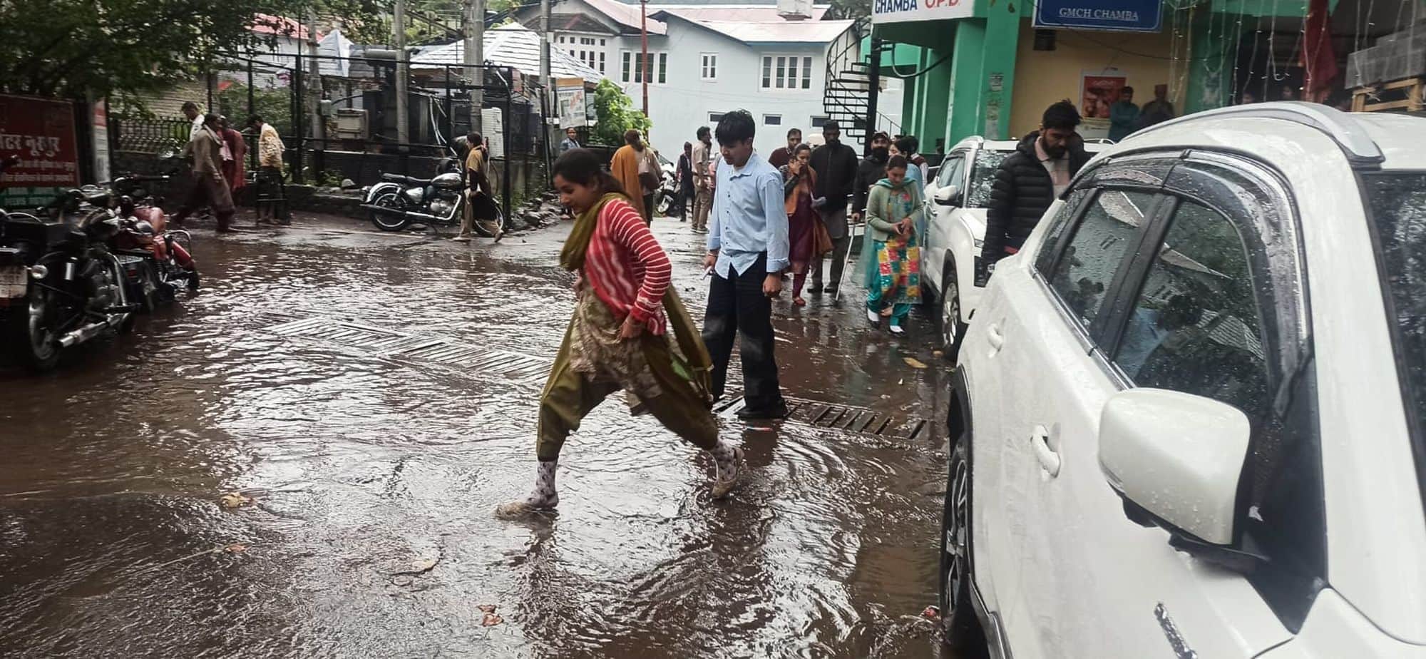 चंबा मेडिकल कॉलेज के मूसलाधार बारिश के बाद मार्ग पर बह रहे पानी के बिच छलांग लगाकार पार करती यु
