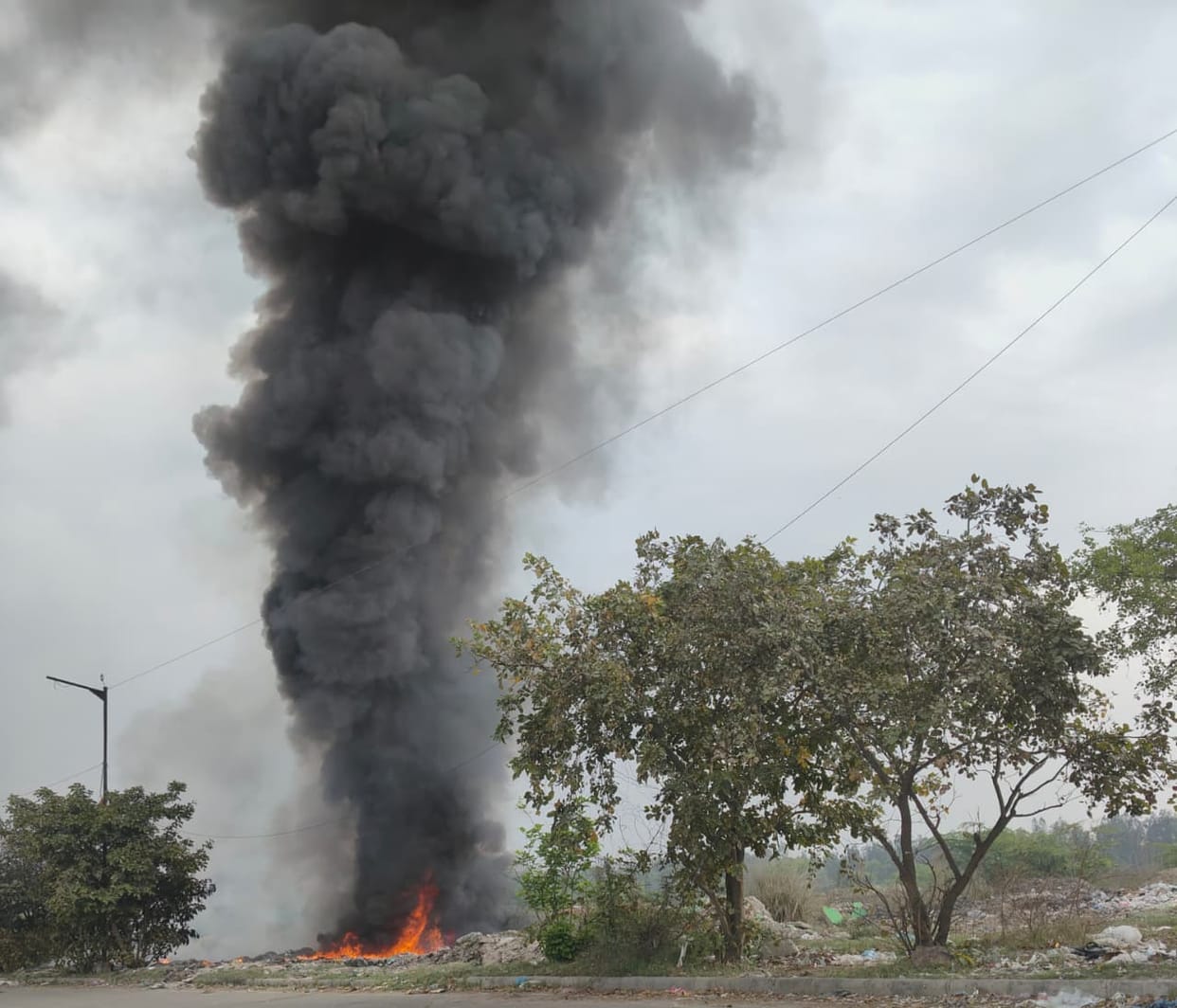 Garbage is being burnt in the open in a large industrial area.
