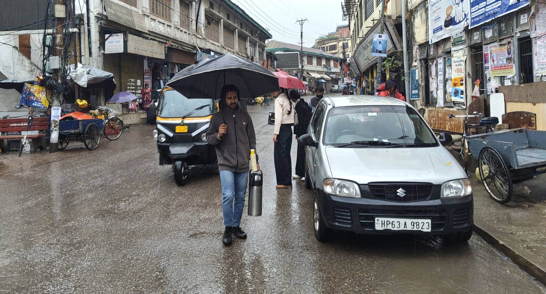 सोलन शहर के मालरोड पर बारिशमें छाता लेकर घूमते लोग। संवाद