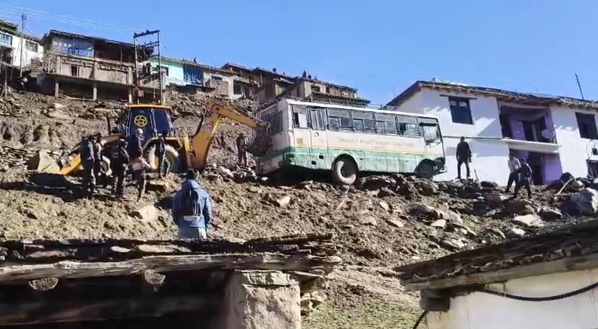 चंबा के पांगी में हवा में लटकी परिवहन निगम की बस को जेसीबी के सहारे निकालता चालक।