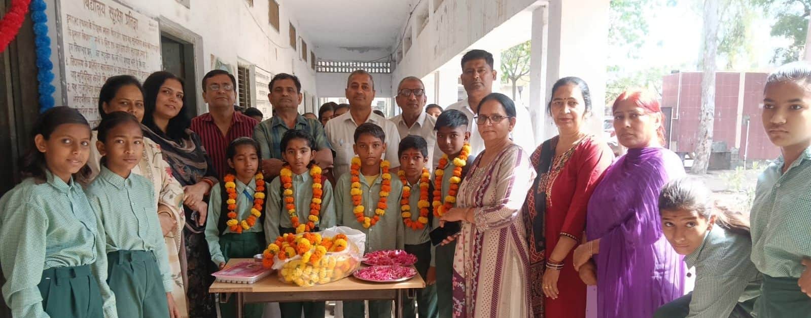 01जेएनडी07: रधाना गांव में विद्यार्थियों को माला पहनाकर स्वागत करते हुए स्कूल सदस्य। स्रोत संस