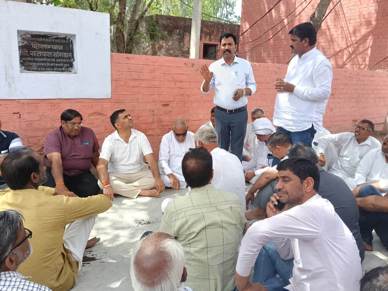 अनाज मंडी में मार्केट कमेटी कार्यालय के बाहर बैठक में सचिव से बात करते हुए आढ़ती। 