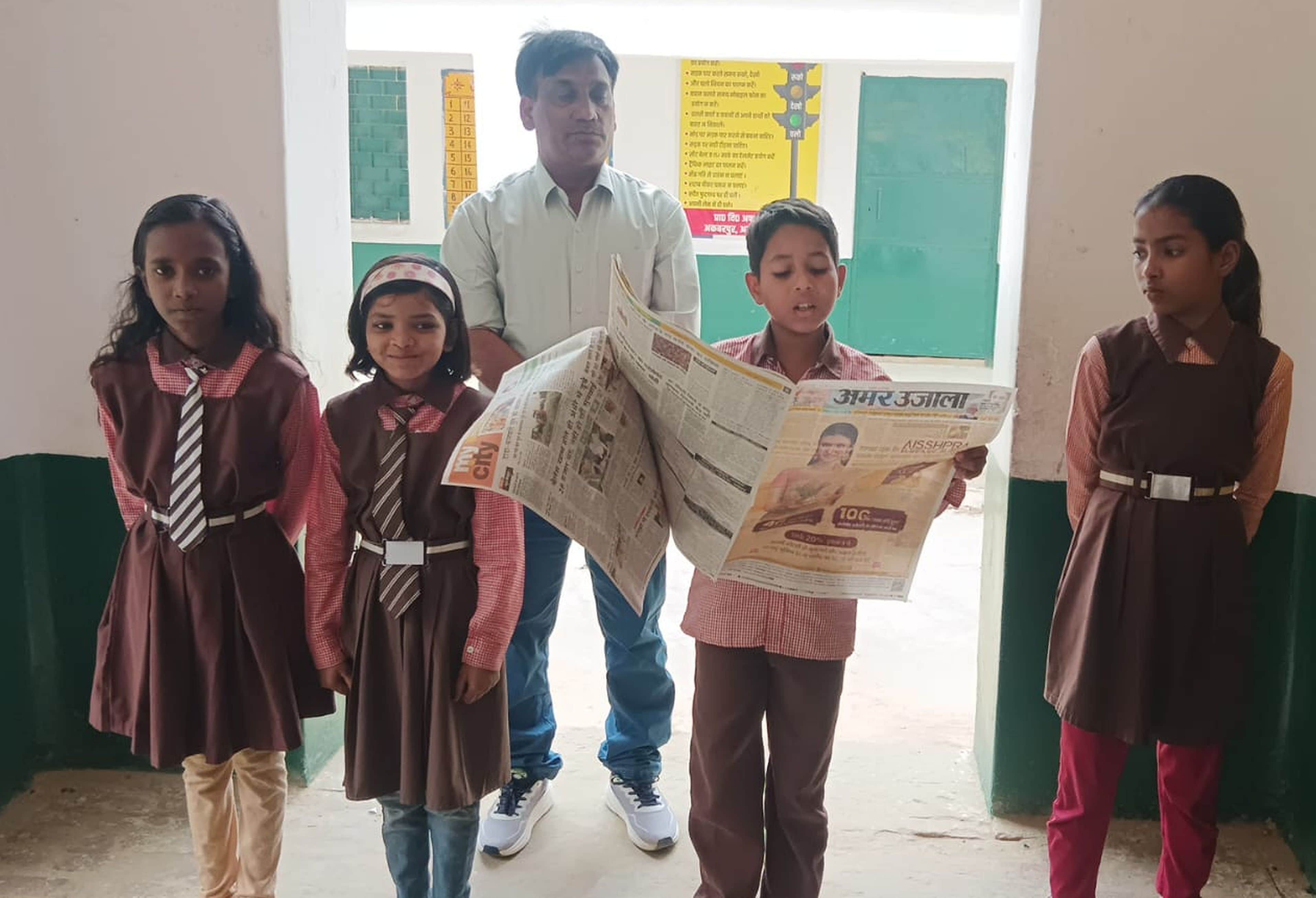 प्राथमिक विद्यालय अफजलपुर में अमर उजाला की सुर्खिंयां पढ़ते बच्चे।