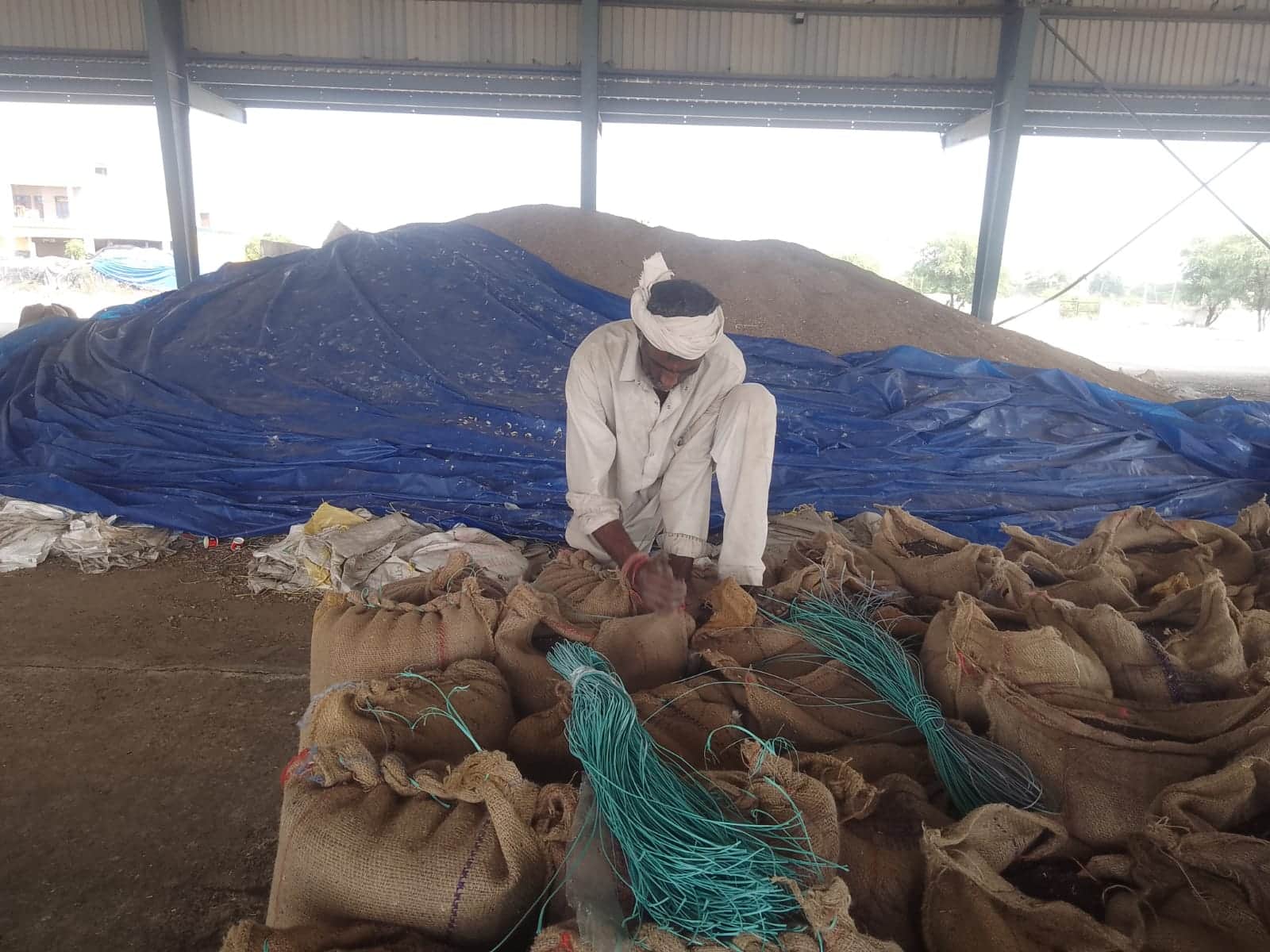 फोटो नंबर- 11व्यापारियों द्वारा खरीदी गई सरसों के बैग की सिलाई करता श्रमिक। संवाद