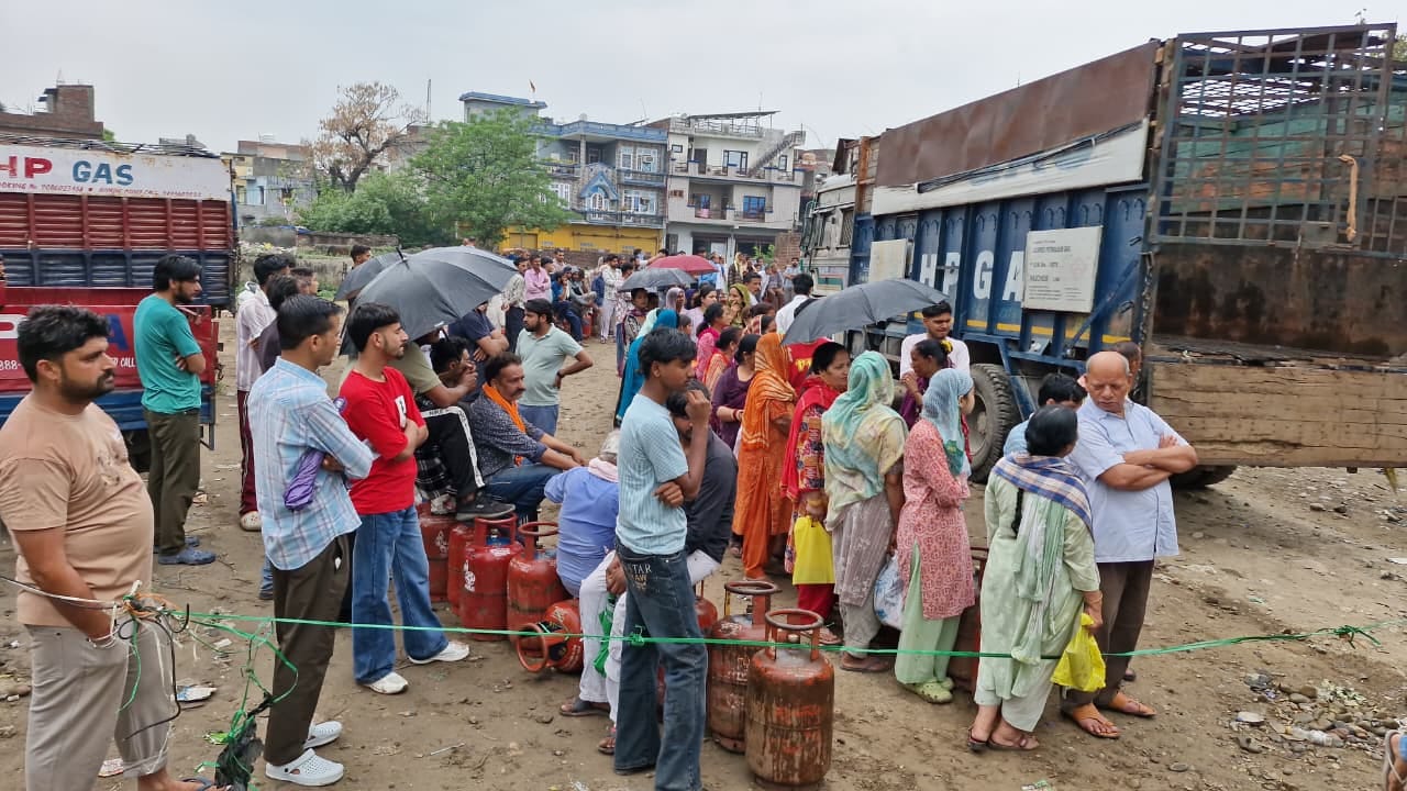 बारिश के दौरान रसोई गैस सिलेंडर लेने पहुंचे उपभोक्ता। संवाद