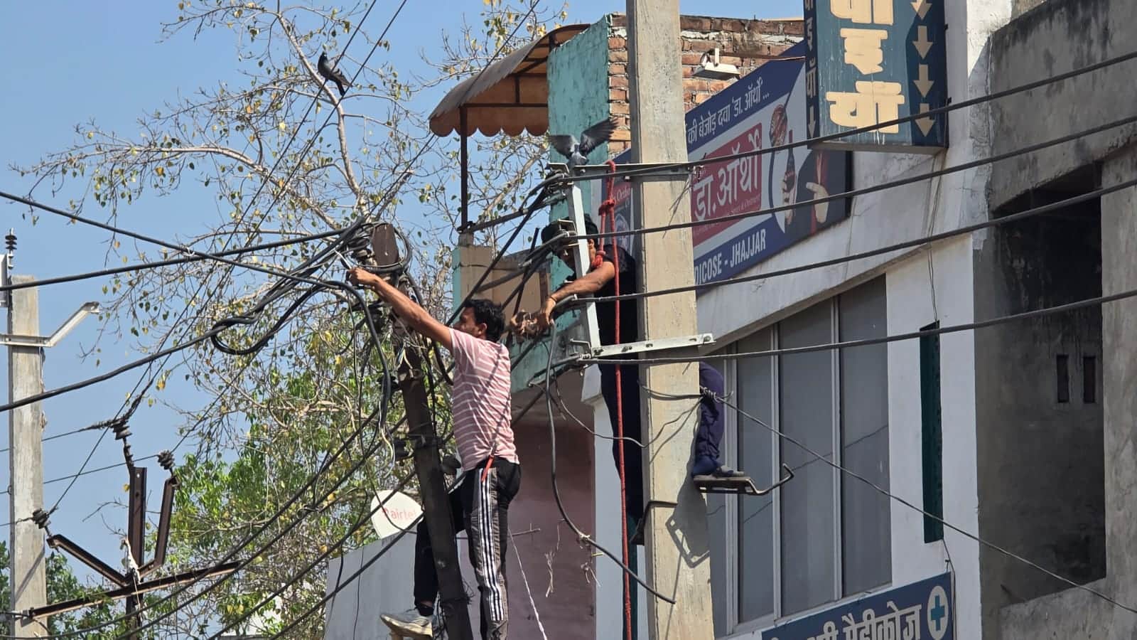 05jjrp05- झज्जर। शहर में लोहे के खंभों से तारों को सीमेंटिड खंभों पर शिफ्ट करते कर्मचारी। संव