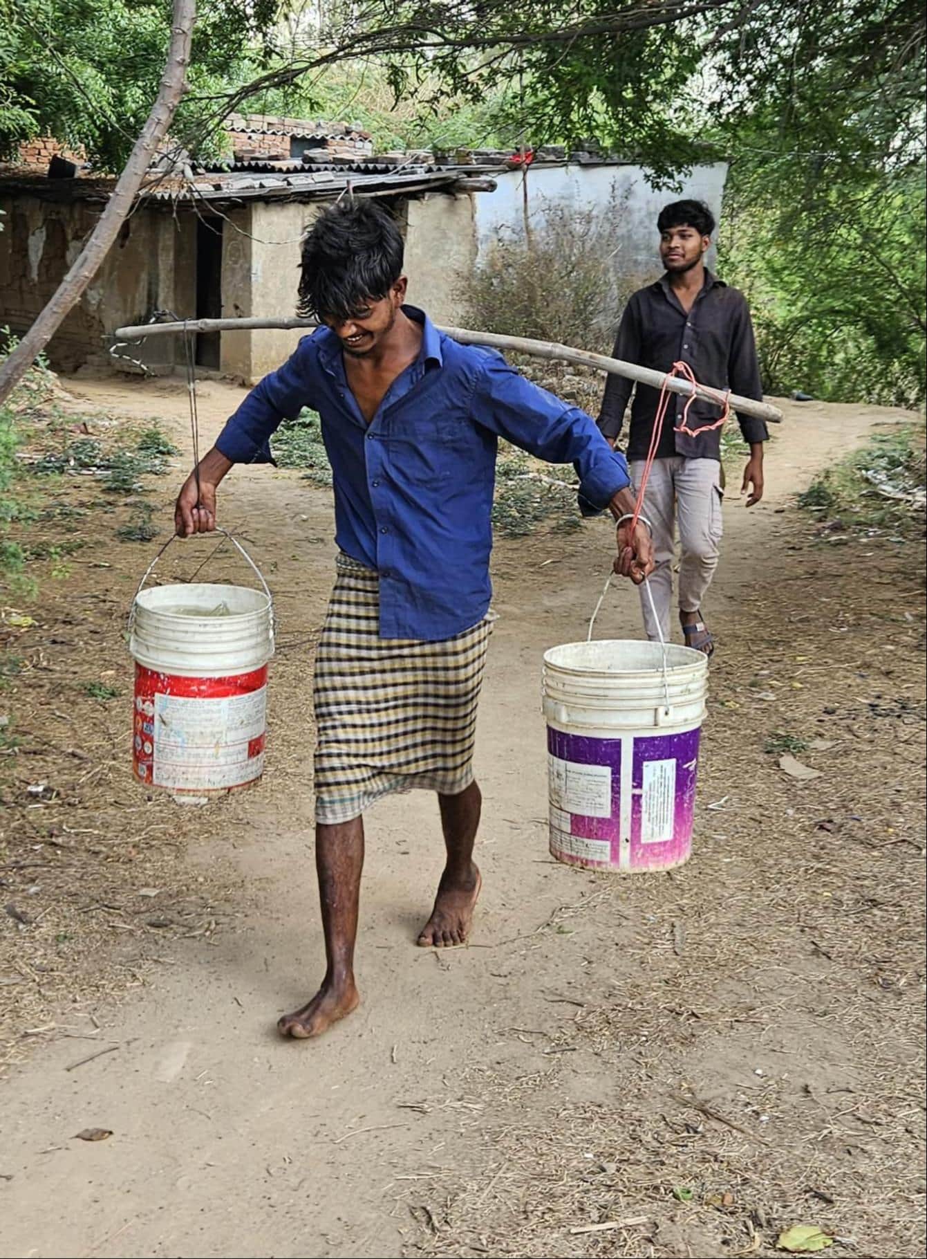अनपरा नगर पंचायत में घर के लिए कंधे पर पानी लेकर जाता युवक। संवाद