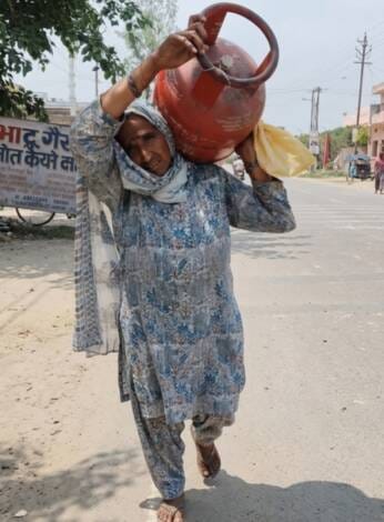 A 55-year-old woman is making rounds of agencies carrying a cylinder on her shoulder.