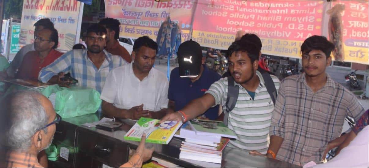 शहर की एक दुकान से किताबें खरीदते अभिभावक व अन्य लोग। संवाद