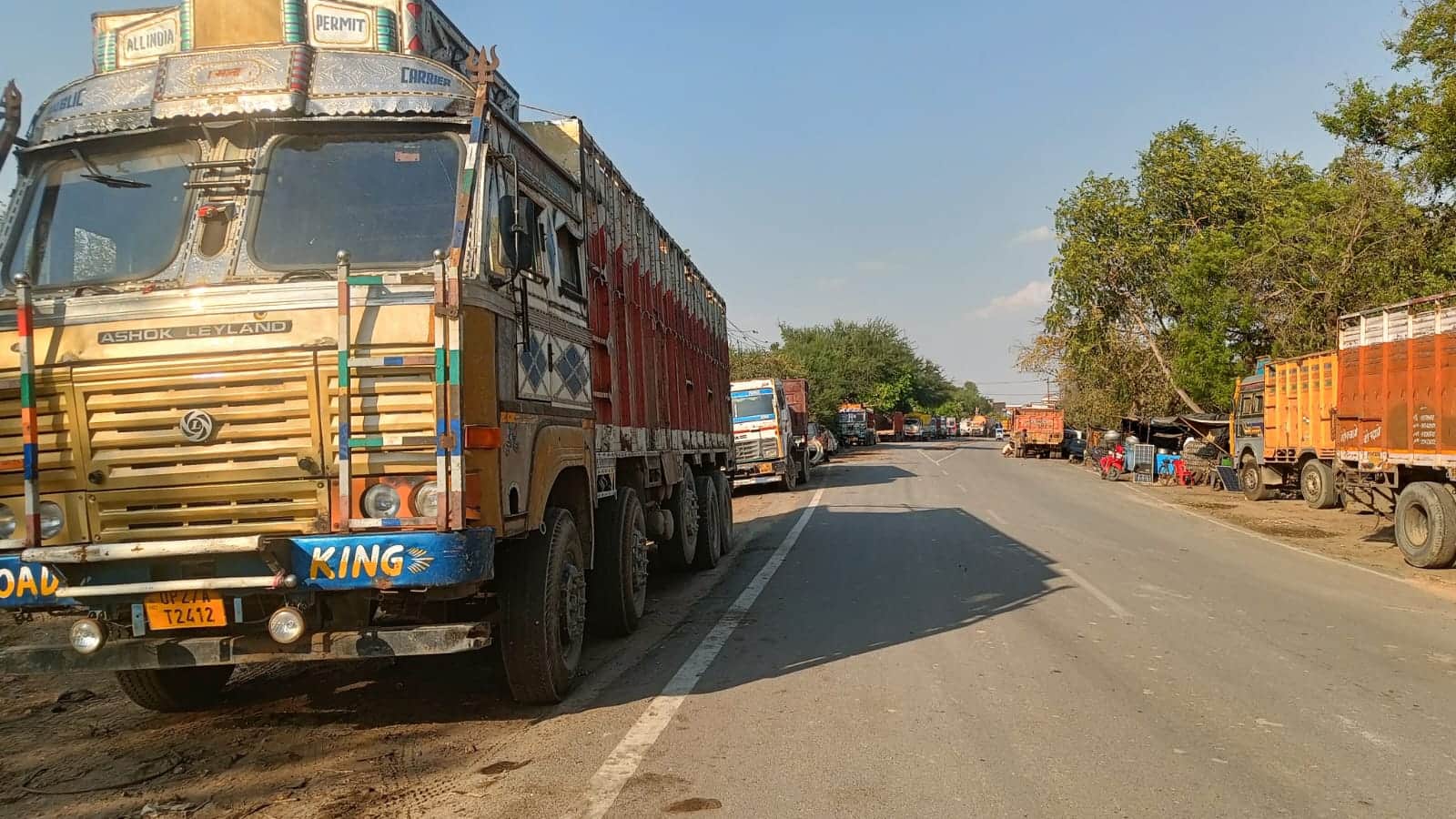 लखनऊ-दिल्ली नेशनल हाईवे पर रोजा क्षेत्र में सड़क पर खड़े ट्रक। संवाद