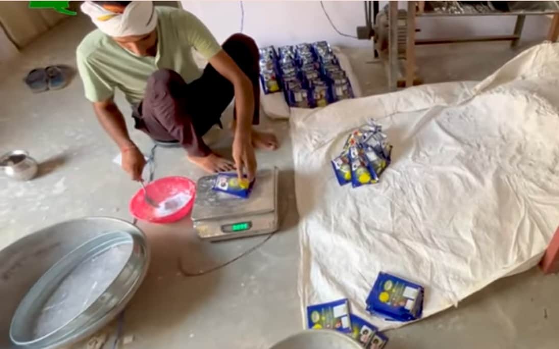 वाशिंग पाउडर की पैकिंग करता मजदूर। आर्काइव