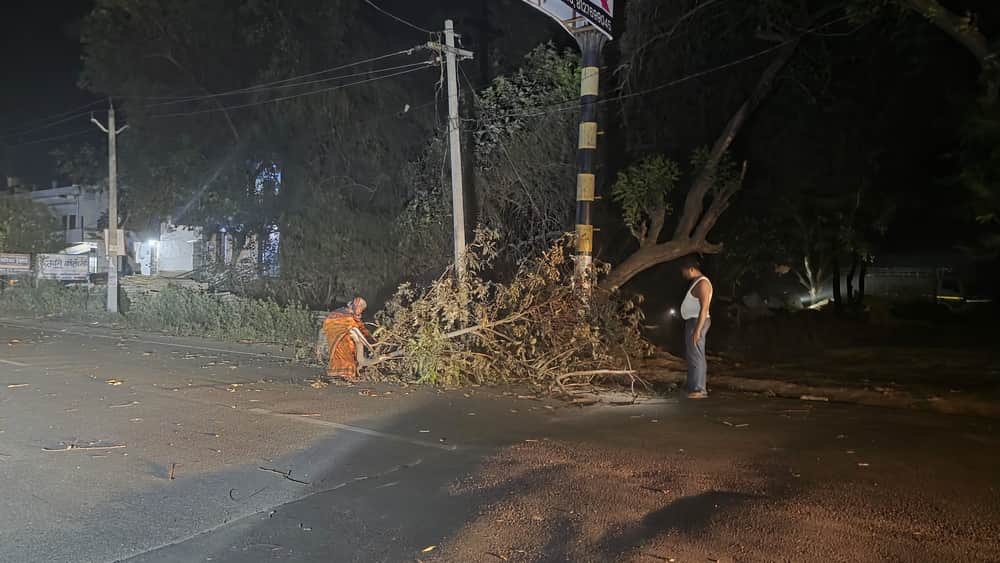 अकबरपुर शहर में बसखारी मार्ग पर मंगलवार रात आंधी के दौरान गिरी पेड़ की डाल को हटाते लोग। संवाद