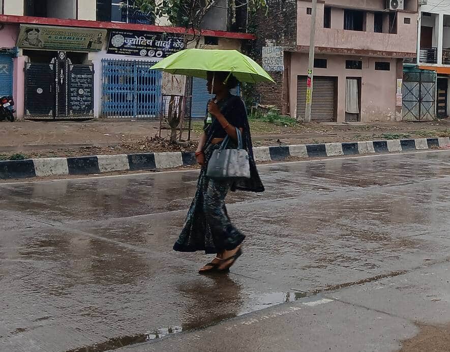 छाता लेकर जाती महिला।