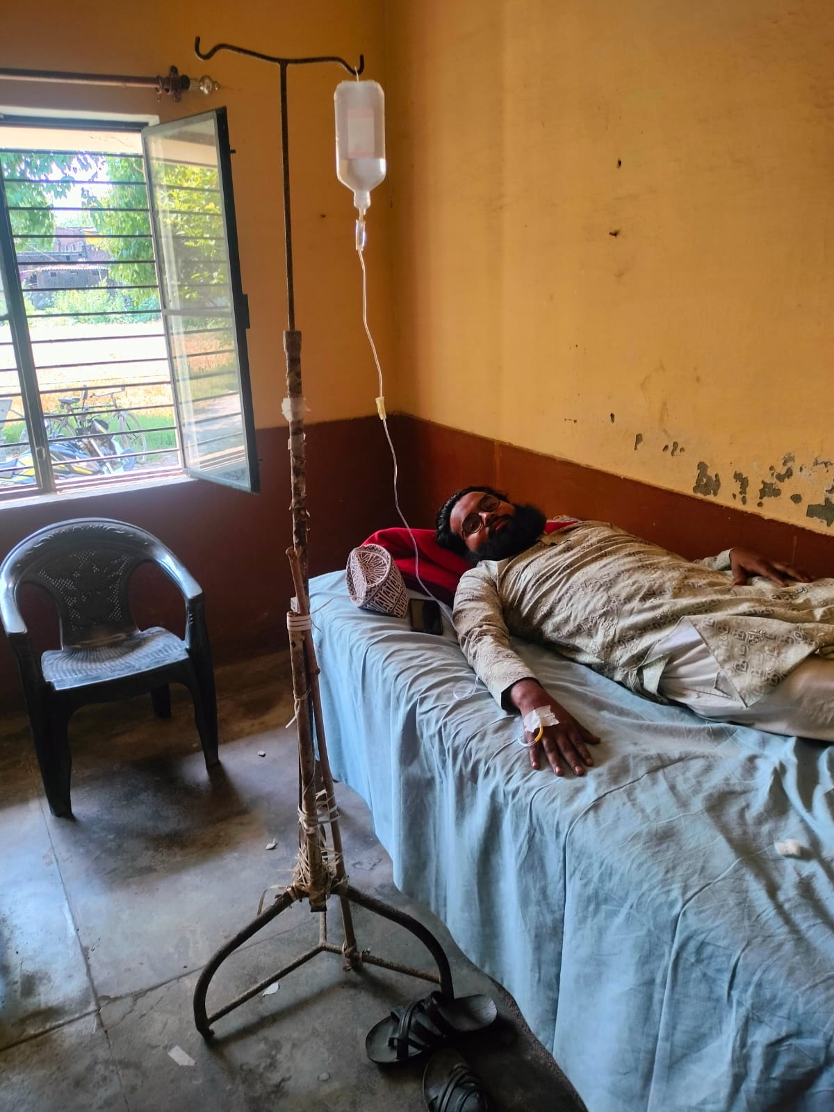 Hospital or makeshift hospital... a dilapidated bed, a drip supported by wood
