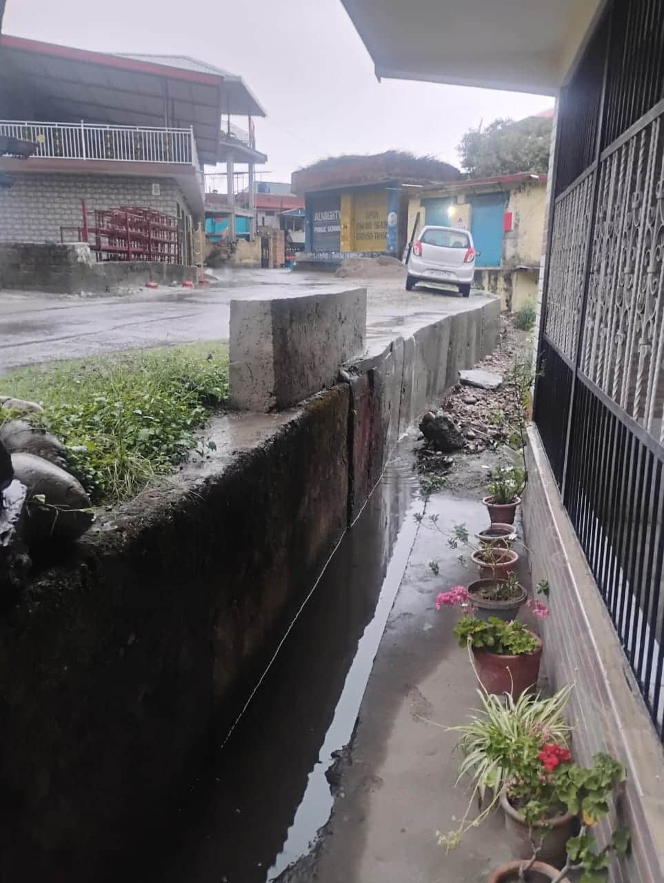 लगदेवी में निकासी नाली के अभाव में सड़क से नीचे गिरते पानी से मकान को खतर। संवाद